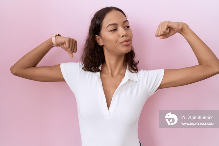 Young hispanic woman wearing casual white t shirt showing arms muscles smiling proud. fitness concept.