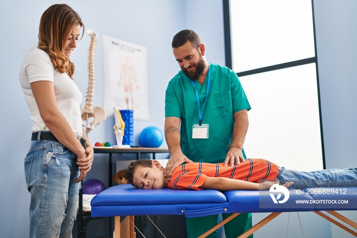 Family having physiotherapy session massaging child back at rehab clinic