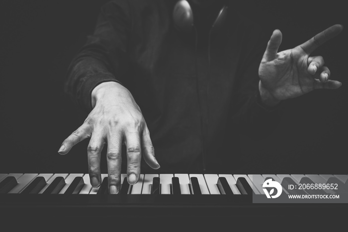 musician hands playing on piano keys, black and white