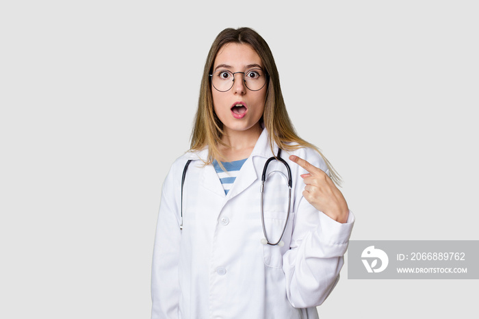 Compassionate female physician with a stethoscope around her neck, ready to diagnose and care for her patients in her signature white coat pointing to the side