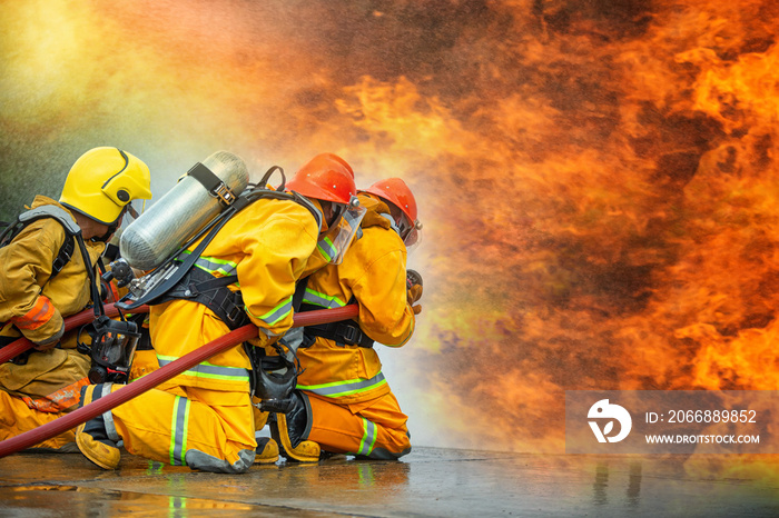 Firefighters spraying high pressure water to fire with copy space, Big bonfire in training, Firefighter wearing a fire suit for safety under the danger case.