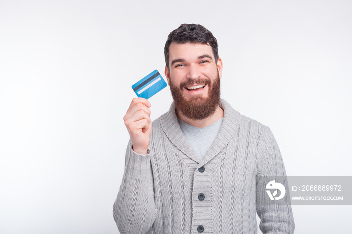 You should get one of this cool credit cards. Excited bearded man is holding a credit card on white background.