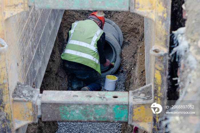 Deep drainage works and groundworker installing concrete pipe protected by trench suppot system