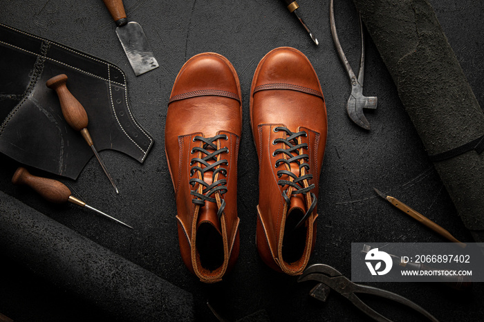 Handcrafted brown leather shoes with cobbler tools on the backgound