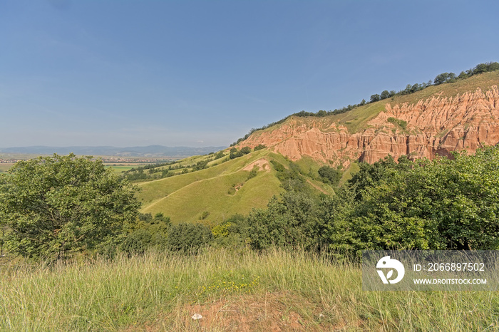 Slopes of Rapa Rosie, the grand canyon of Romania, with orange rocks and green meadows