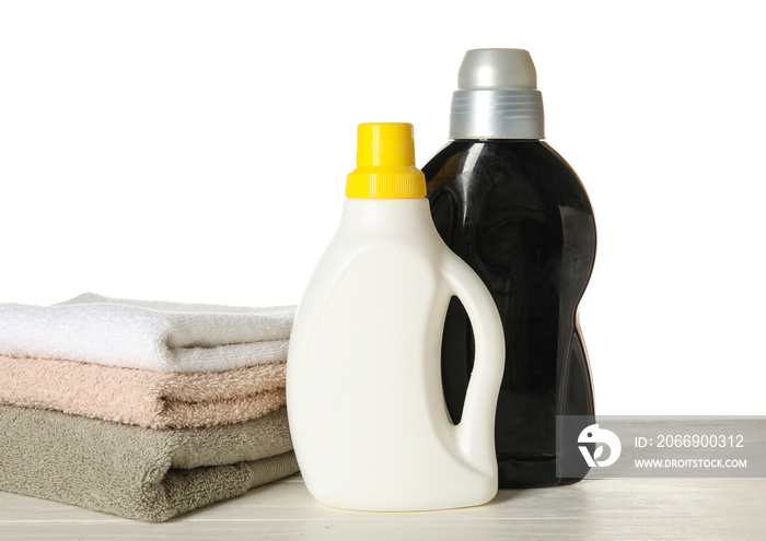 Laundry detergents and towels on table against white background