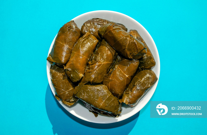 Stuffed Grape leaves in white bowl on blue background. Famous traditional Middle East, Turkish, Asian cuisine. Dolma