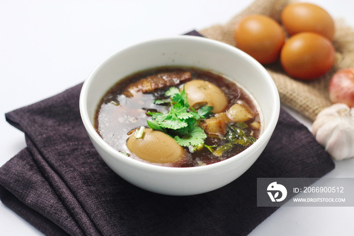 The Thai food we call  Egg and Pork in Sweet Brown Sauce  is served in a white cup. in a restaurant in Thailand