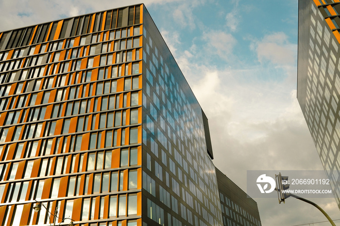 Wide angle view of modern corporate office building architecture with glass and metallic construction with reflection against blue clouds located in Lodz, Poland