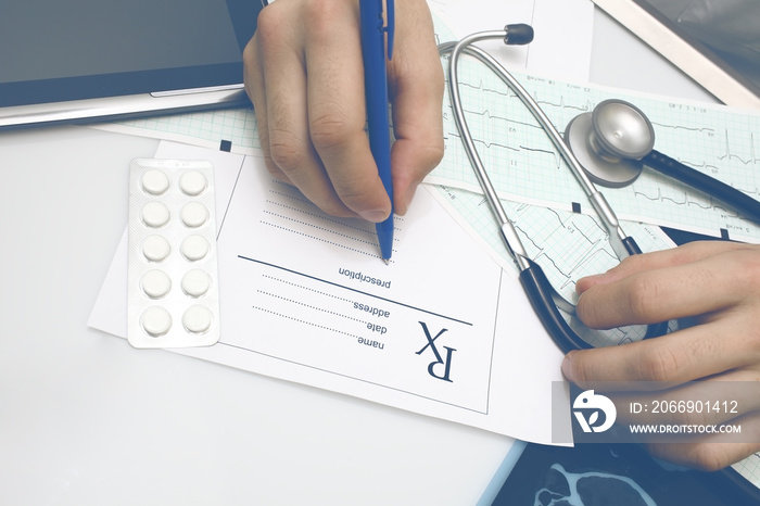 Male doctor fills in the prescription form after examination of patient