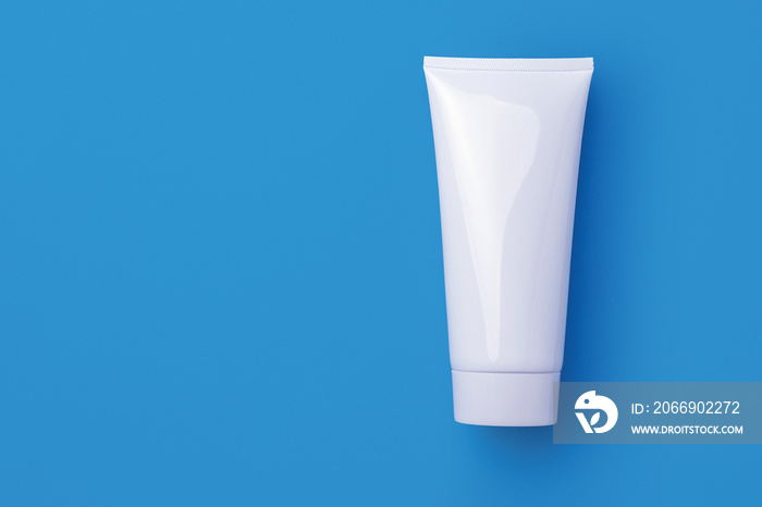 Blank white cosmetic tube isolated on blue background.