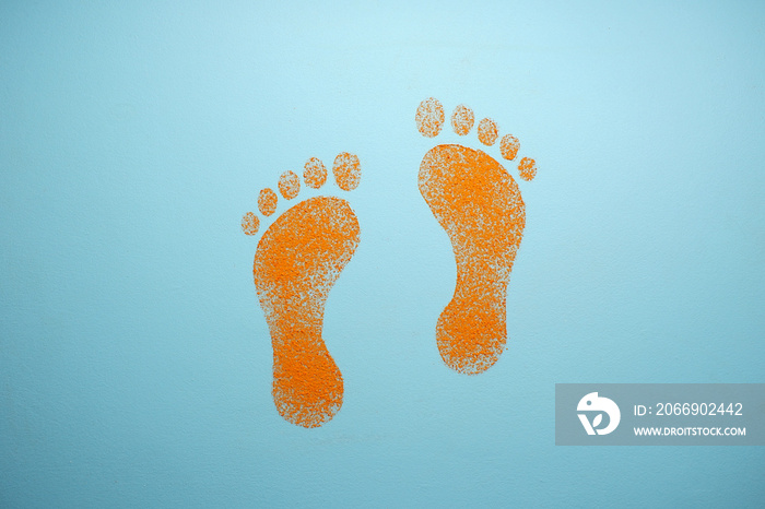 Drawing on a blue background. Orange human footprints