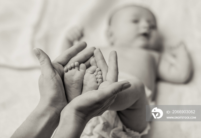 Mother holding tiny foot of newborn baby