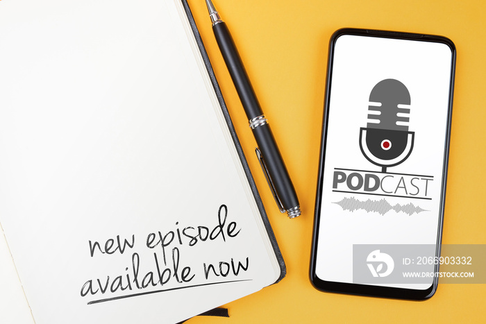 podcasting concept, text NEW EPISODE AVAILABLE NOW written on note pad and smartphone with podcast player mockup on orange desk