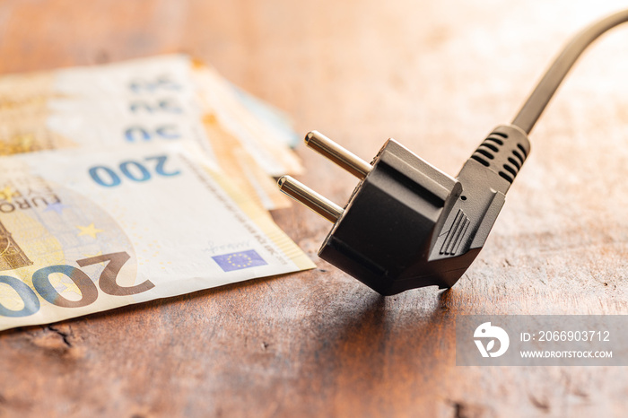 Electric plug and euro money on wooden table. Concept of increasing electric prices.