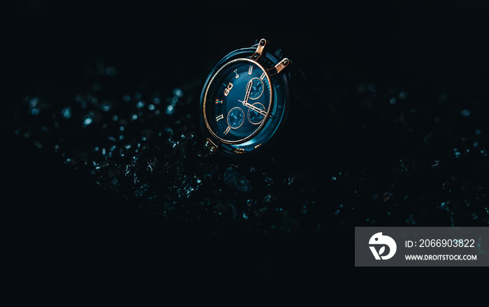 A metallic gold Blue men’s watch on a black background.