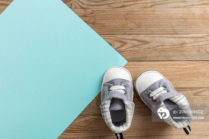 Baby boy shoes on pastel blue and wooden background