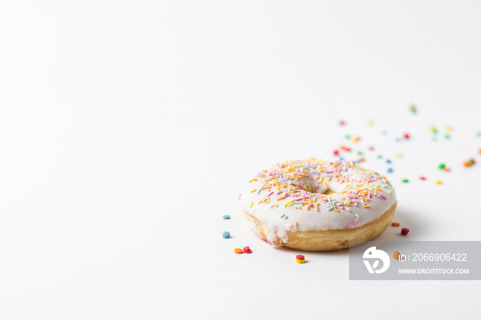 Fresh tasty donut and sweet multicolored decorative candy on a white background. Bakery concept, fresh pastries, delicious breakfast.