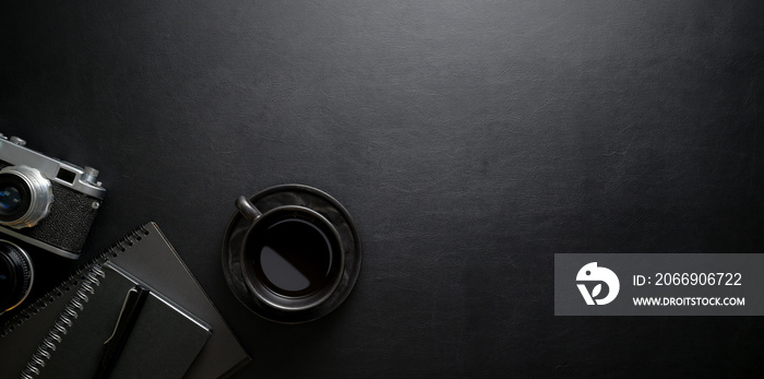 Dark stylish workplace with coffee cup and office supplies on black leather table background