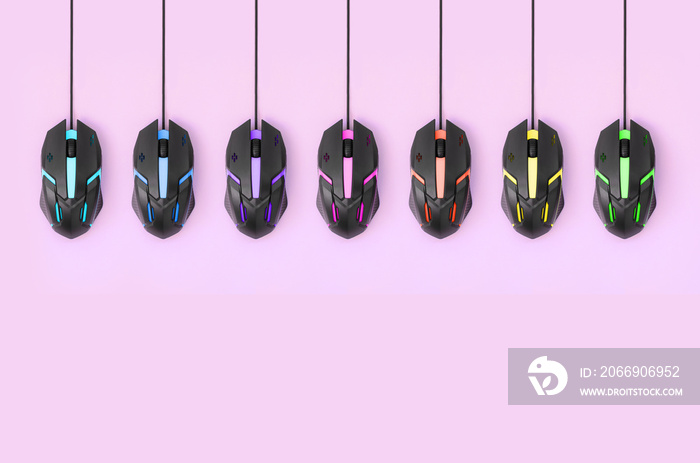 Black computer mouses hang on pastel pink background