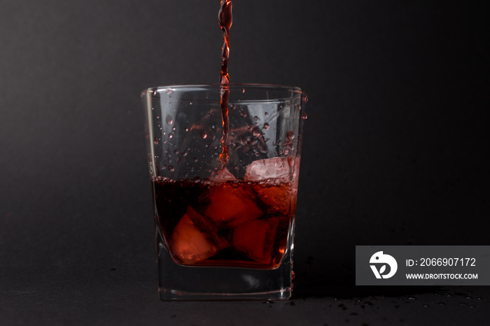 Vaso pequeño con hielo y whiskey en un fondo negro