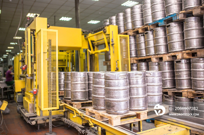 Brewery, bottling beer on aluminum kegs on conveyor lines. Industrial work, automated modern food and beverage production.