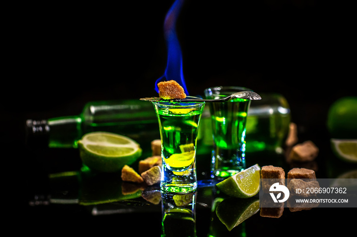 absinthe shots with sugar cubes. absinthe poured into a glass. bottle of absinthe with brown sugar and lime isolated on black background. space for text