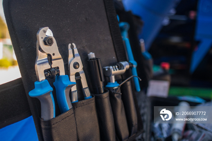 An assortment of modern blue coloured bicycle tools in a tool box or pouch on a work bench.