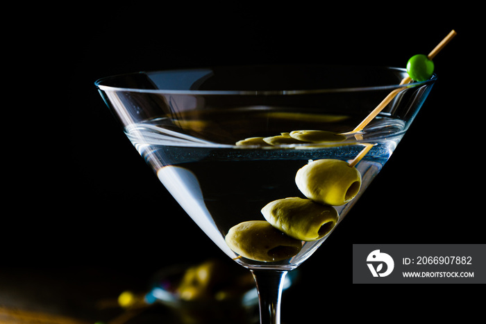 Elegant glass of dry martini with olives on a black background. Horizontal orientation.