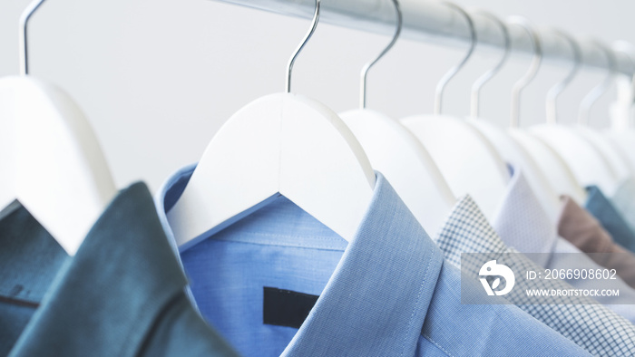 Assorted blue shirts hanging on wooden hangers