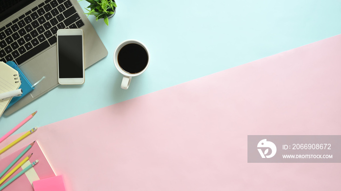 Copy space pastel office desk with laptop, smartphone and office supplies with coffee on top view table.