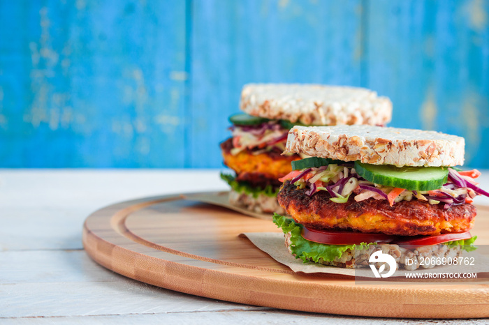 healthy vegan burgers with rice cracker  carrot cutlet lettuce coleslaw tomato cucumber on cutting board copy space