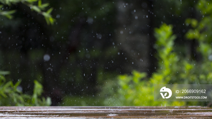 drops of rain fall on a wooden terrace and a bridge near the pool