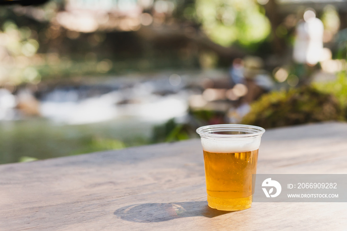 Isolated of beer in plastic glasse on wooden table.