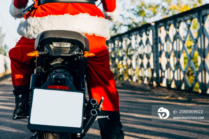 Santa Claus riding a motorcycle on his back wit copy space for text.