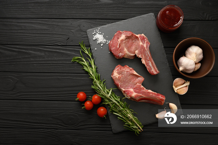 Raw cowboy steak and spices on a black wooden background. BBQ Top view. Free space for text.