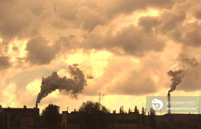 Industrial plant pollutes atmosphere and environment with harmful emissions from chemical processing through factory chimneys against cloudy sky