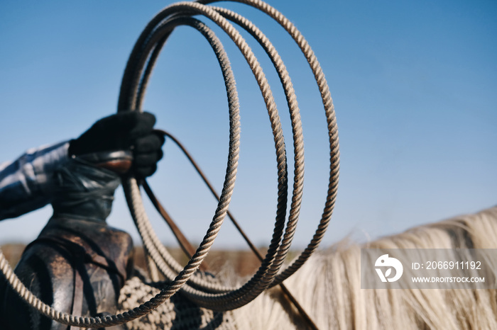 Close up of rope in hand of rider on horse, isolated on sky background, rodeo roping lifestyle.