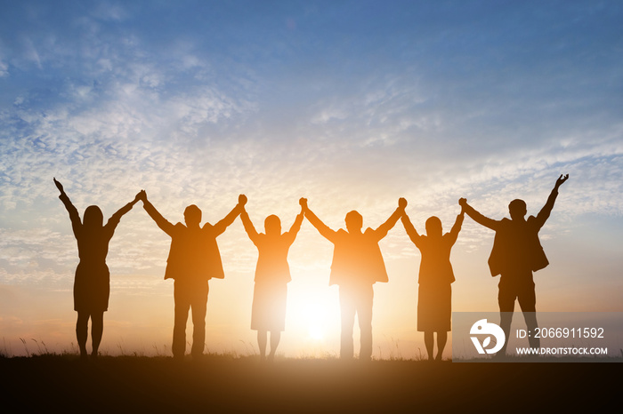 Silhouette of happy business teamwork making high hands over head in sunset sky background for business teamwork concept