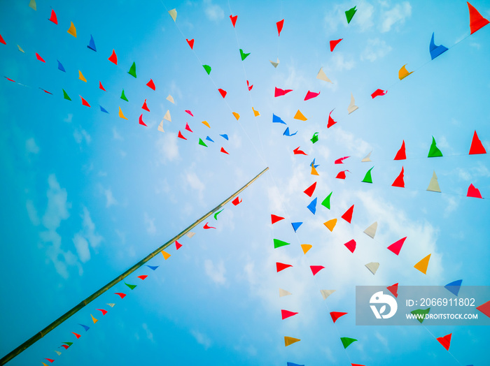 Colorful flags, colorful party decorations, small triangular flags to celebrate the party with the blue sky and clouds as the holiday concept background.