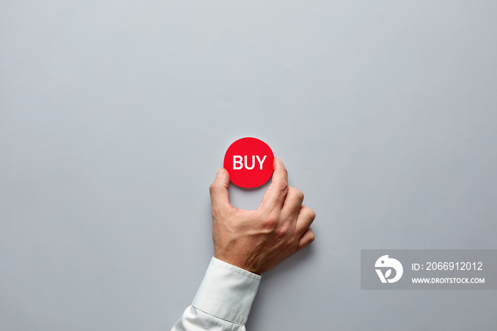 Businessman hand holding a red badge with the word buy. Buying decision in finance or real estate