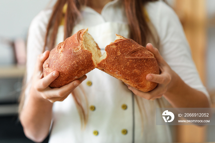 Little baker with fresh bread in kitchen, closeup