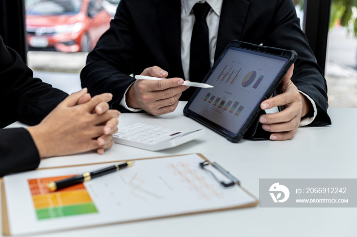 Two people look at the tablet screen showing the company financial summary, business people brainstorm ideas to solve losses and plan strategies to make the company profitable and grow.