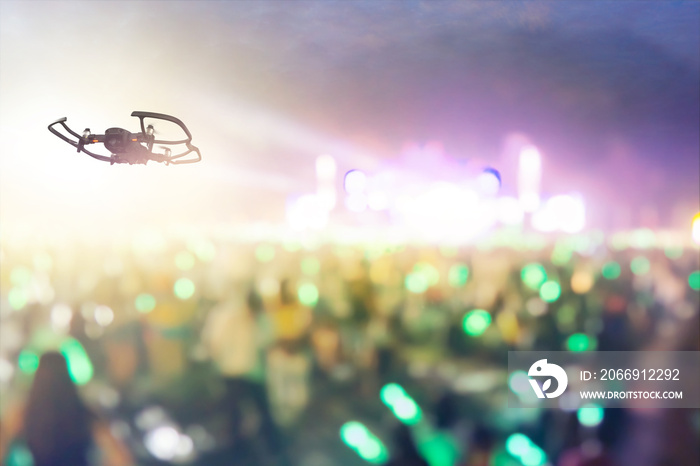 Silhouette of Drone flying for taking video streaming in outdoor concert stage.