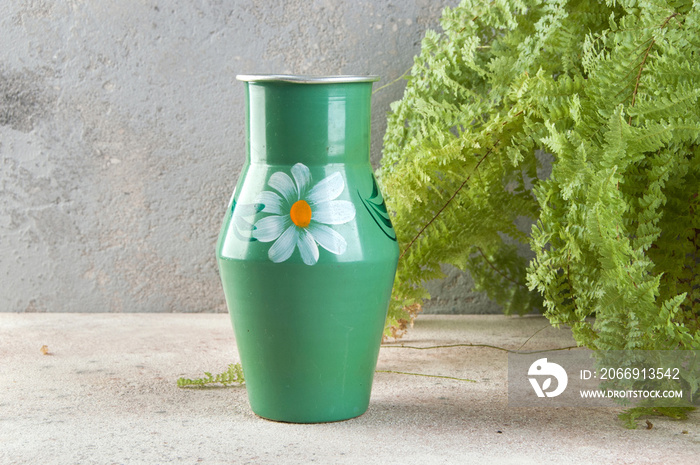 Old metal green vase on a concrete background.