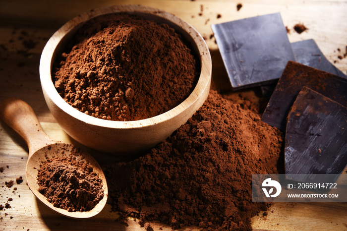 Composition with bowl of cocoa powder on wooden table