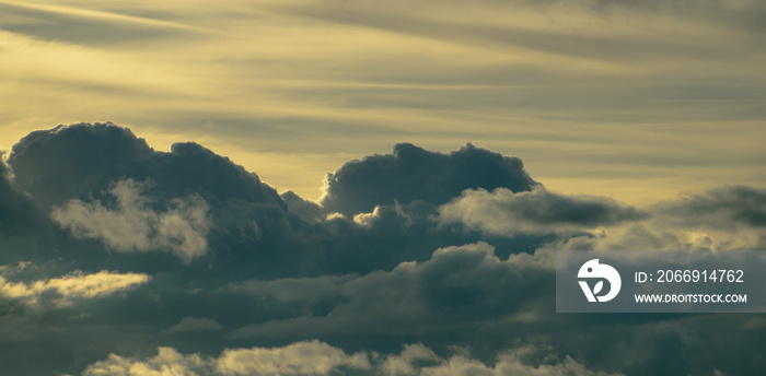 Fluffy yellow clouds after storm going over the horizon. Dark cloudy sky before thunderstorm panoramic background. Storm heaven panorama. Wide gloomy backdrop