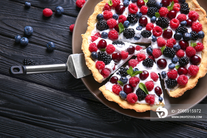 Plate with delicious berry pie on wooden background, top view