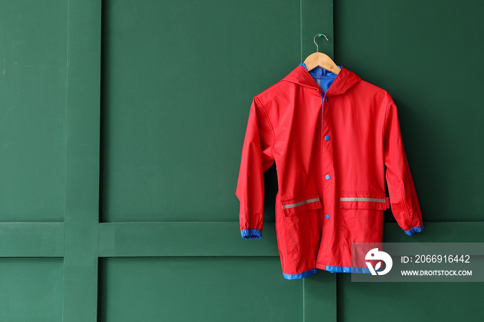 Child’s raincoat hanging on green wall