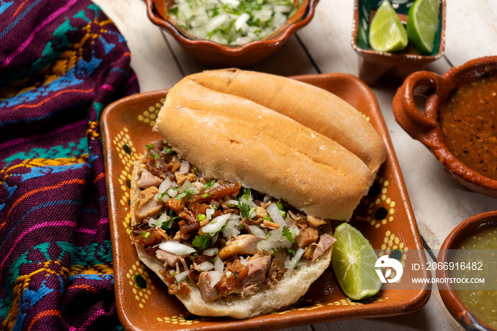 Confit pork sandwich called Torta de carnitas on white background. Mexican food